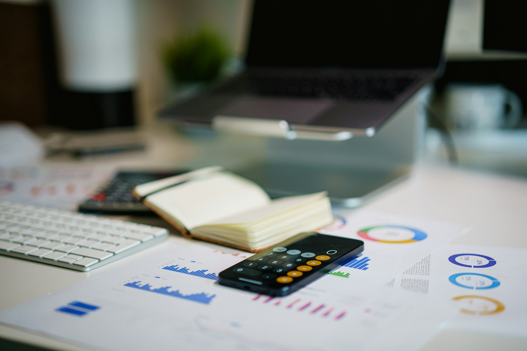 A phone calculator resting on printed financial charts