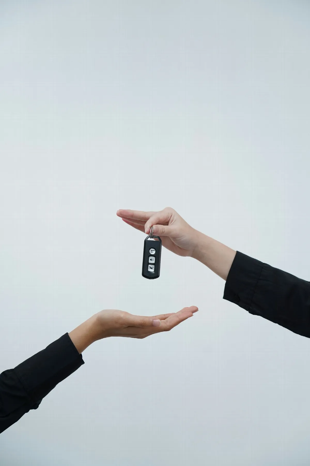 Two hands passing a car key from one person to another