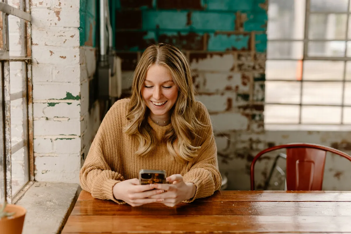 A woman sitting at a table looking down at her cell phone