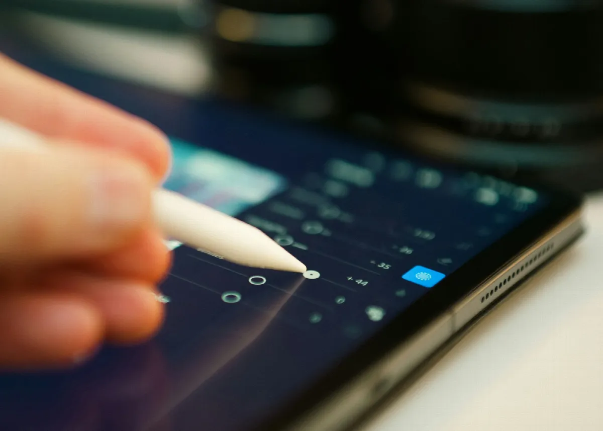 A hand using a stylus on a tablet screen in soft light