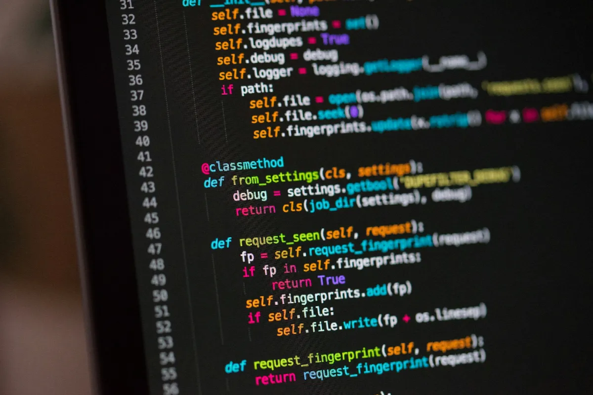 Close-up of a monitor showing colorful lines of Python code in a dark code editor