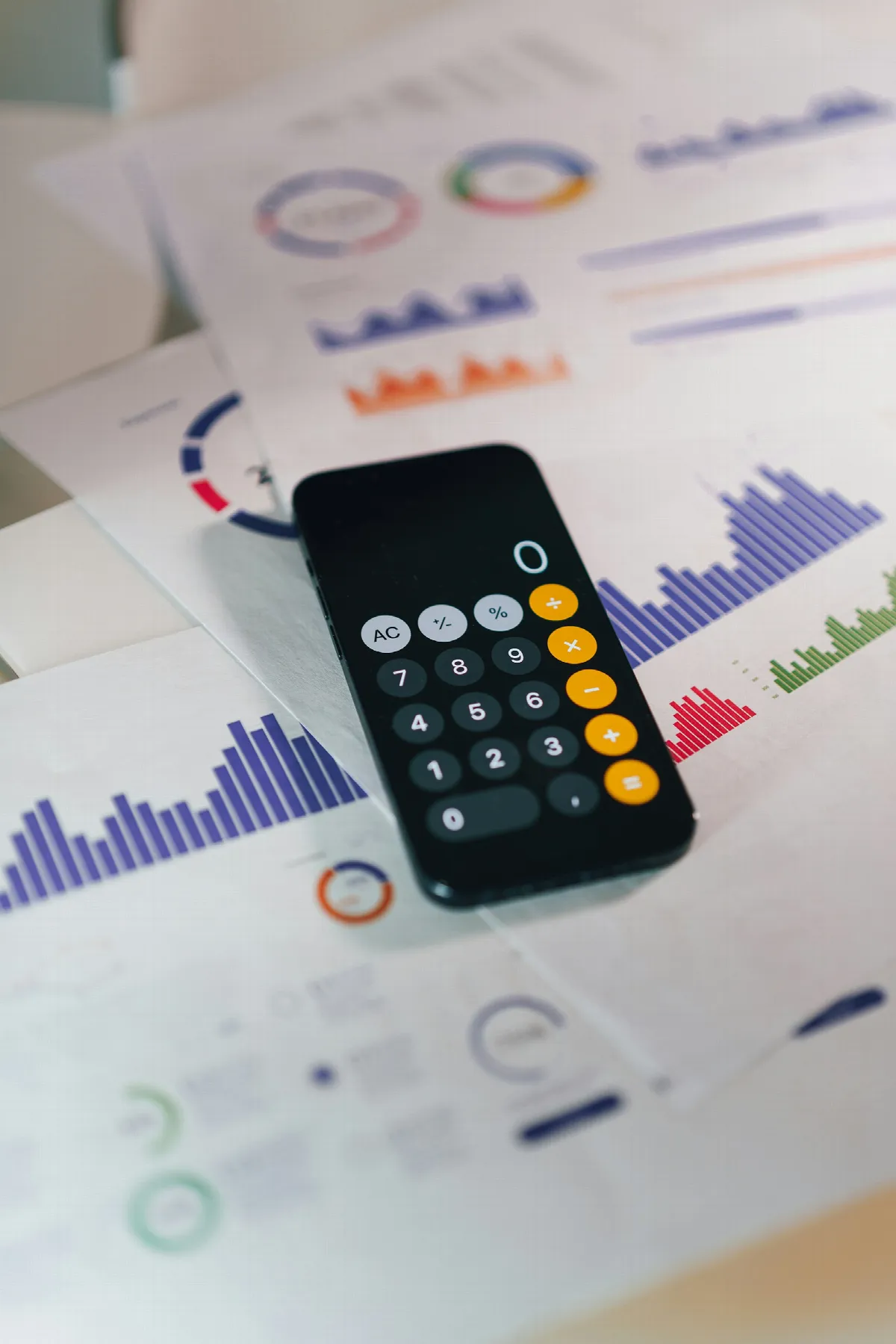 A phone calculator app lying on printed charts, the kind of quick math behind credit report API pricing