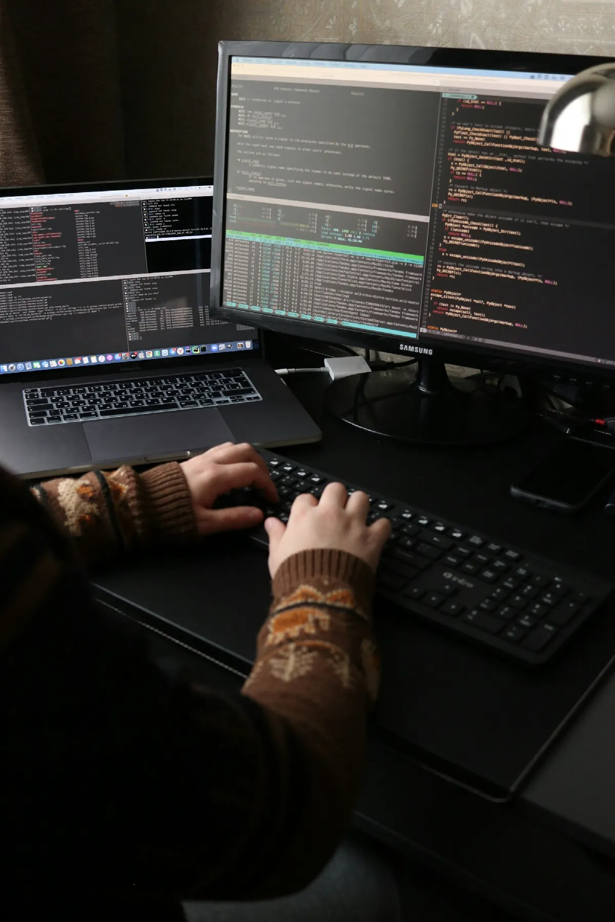 A person working at a desk with a laptop and a large external monitor