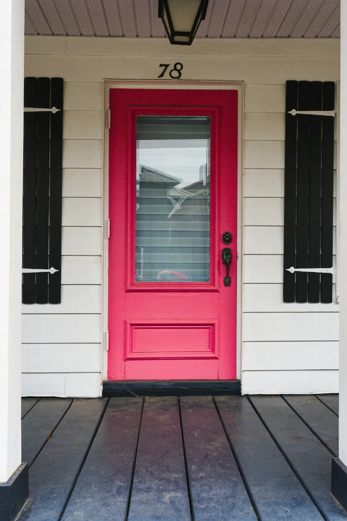 A red front door set into the white wall of a house