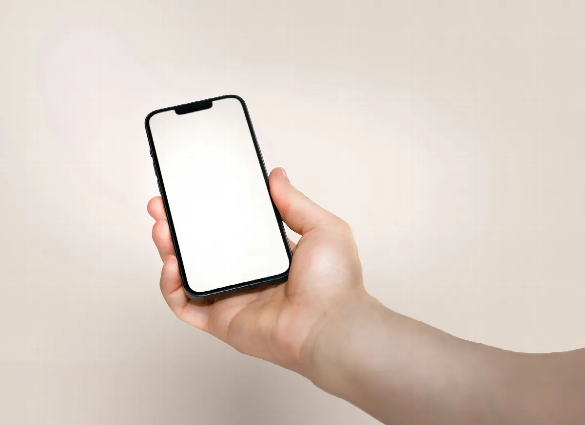 A hand holds up a smartphone with a blank white screen, ready to run a free reverse phone lookup