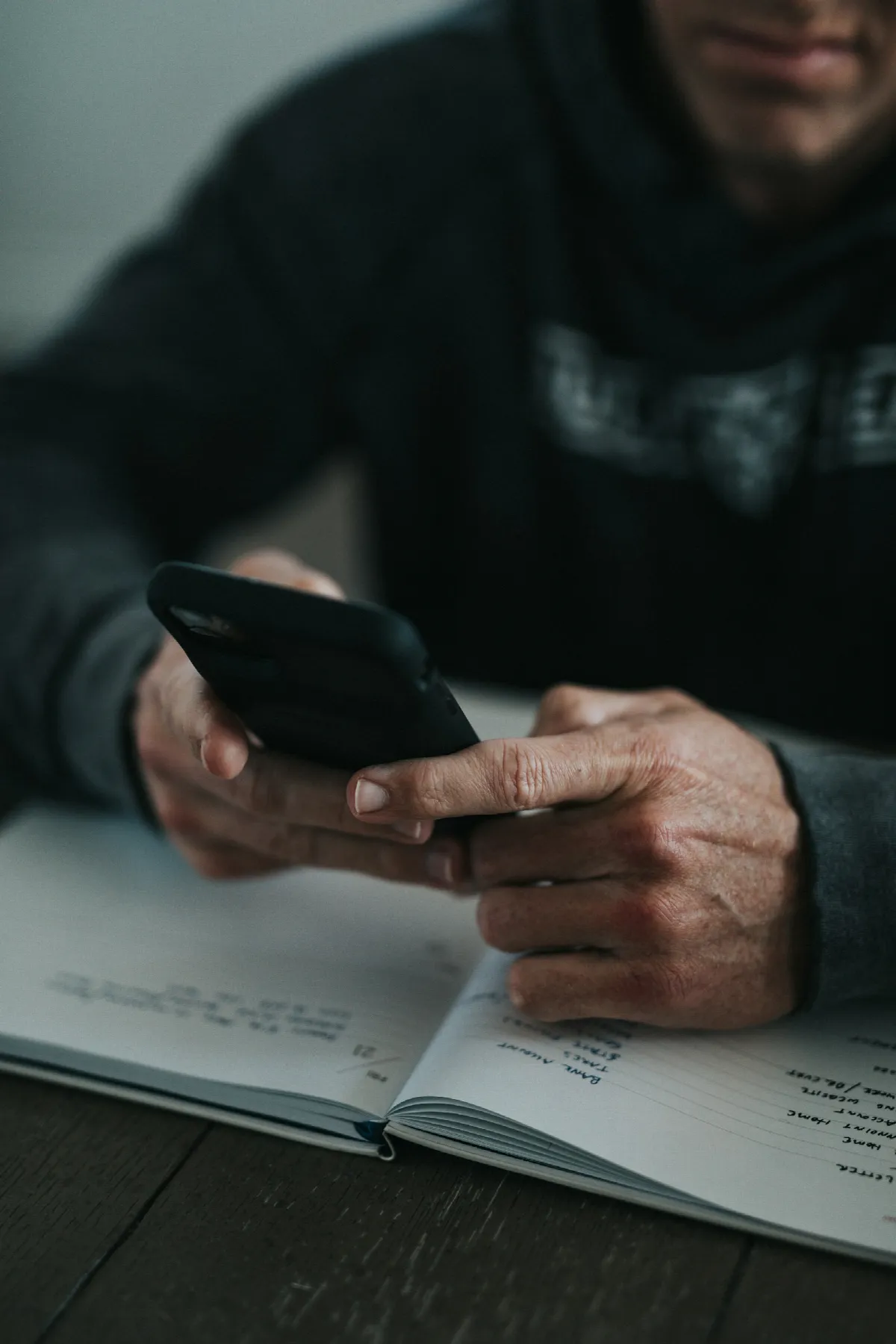 A hand holding a smartphone above a sheet of white paper on a table