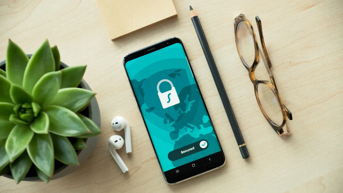 A smartphone showing a security lock icon on a wooden desk next to a small succulent