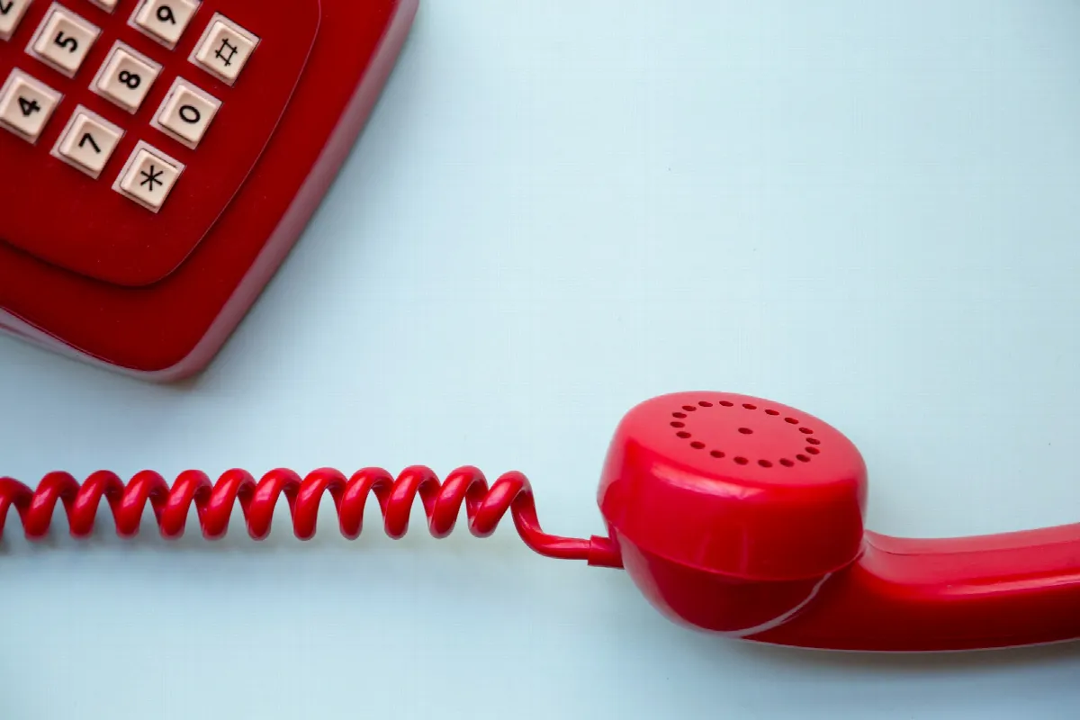 A red corded home telephone resting on a table