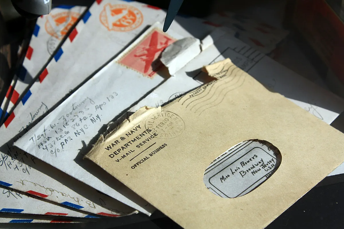 Several opened envelopes with airmail stripes and a window envelope scattered across a dark table