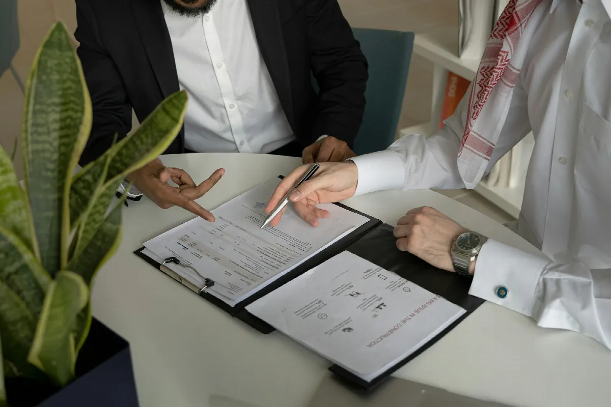 Two people reviewing printed paperwork with a pen at a round white table