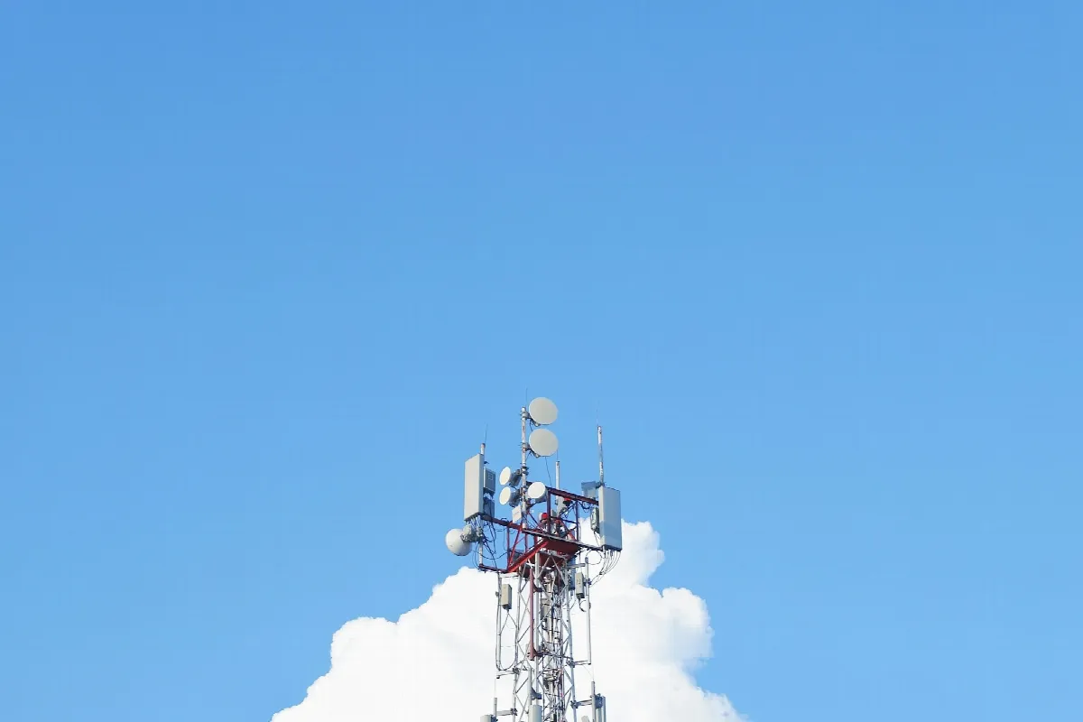 A cell phone tower with several antennas against a clear blue sky