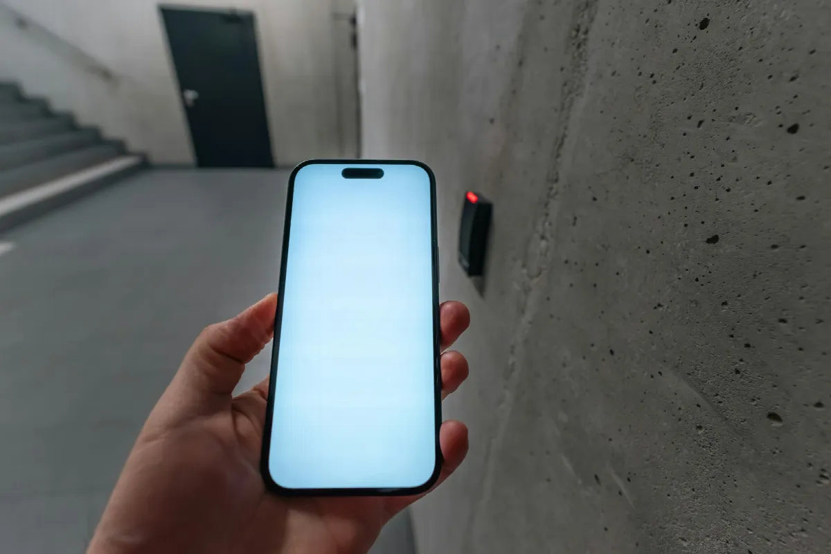 A person holds a smartphone up to an electronic lock beside a secured door