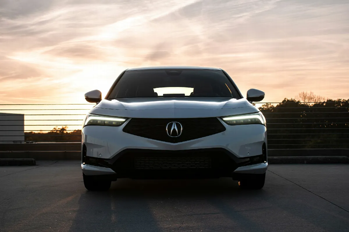 A white sedan parked facing the camera on an empty rooftop lot at sunset