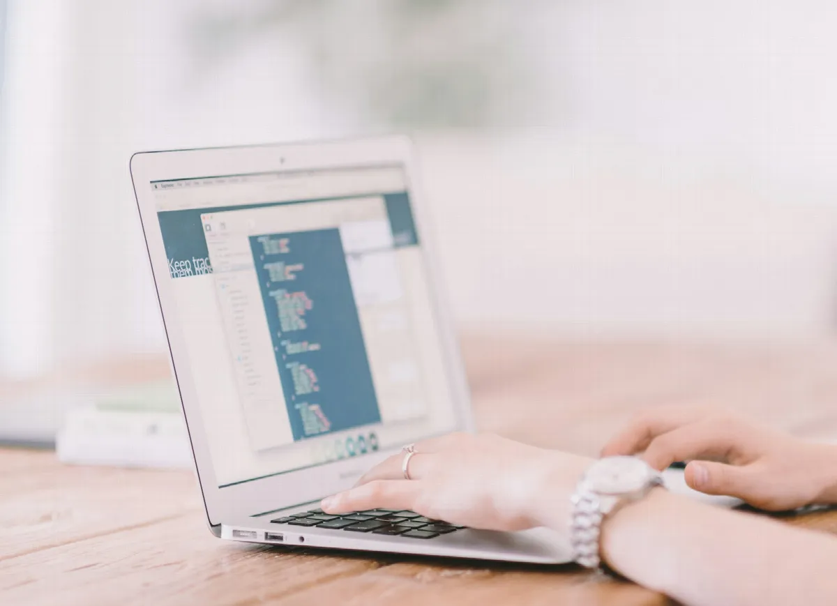 A person typing into an online application on a laptop at a wooden table, the kind of form synthetic identity fraud targets