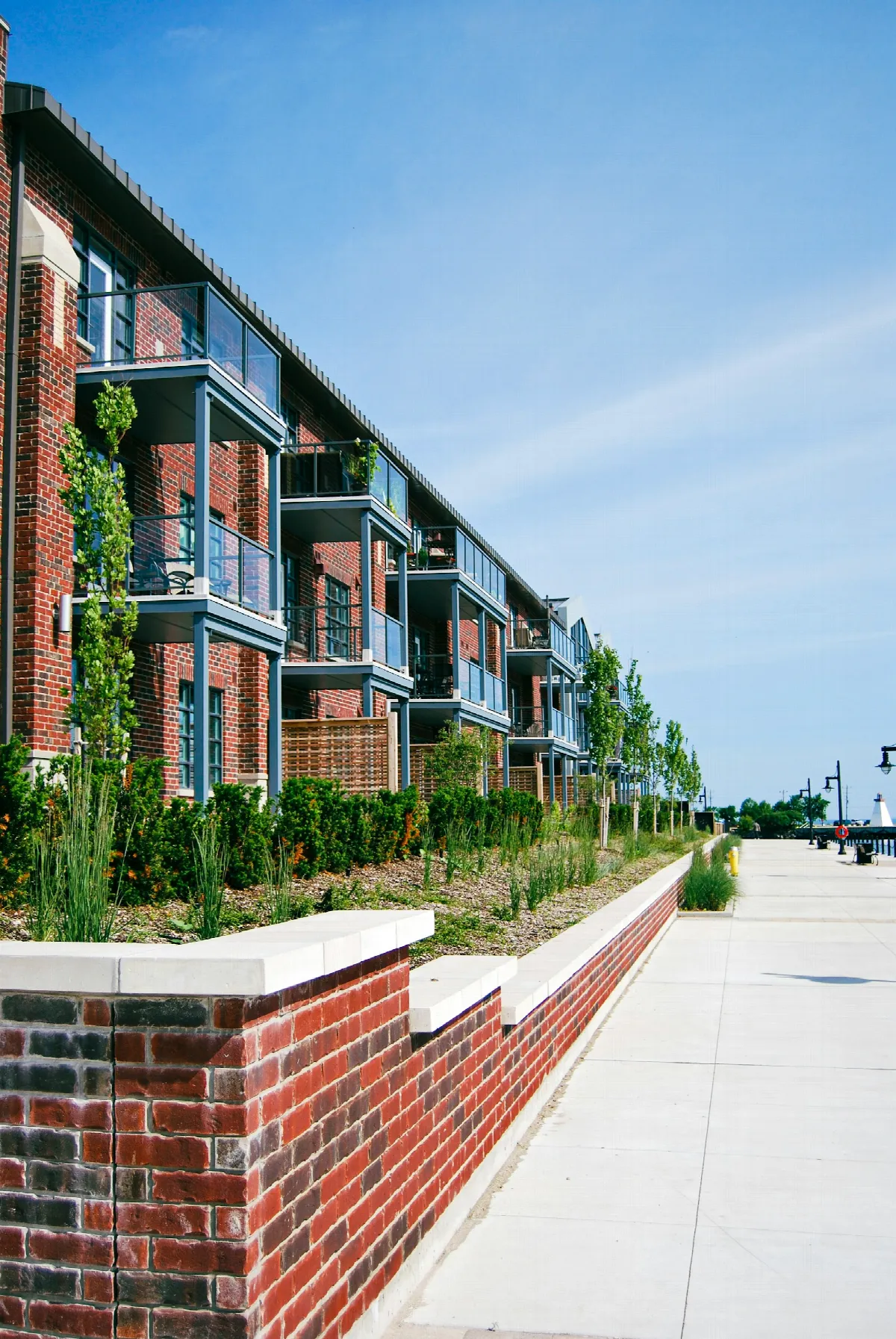 A red brick apartment building with rows of small balconies against a clear sky