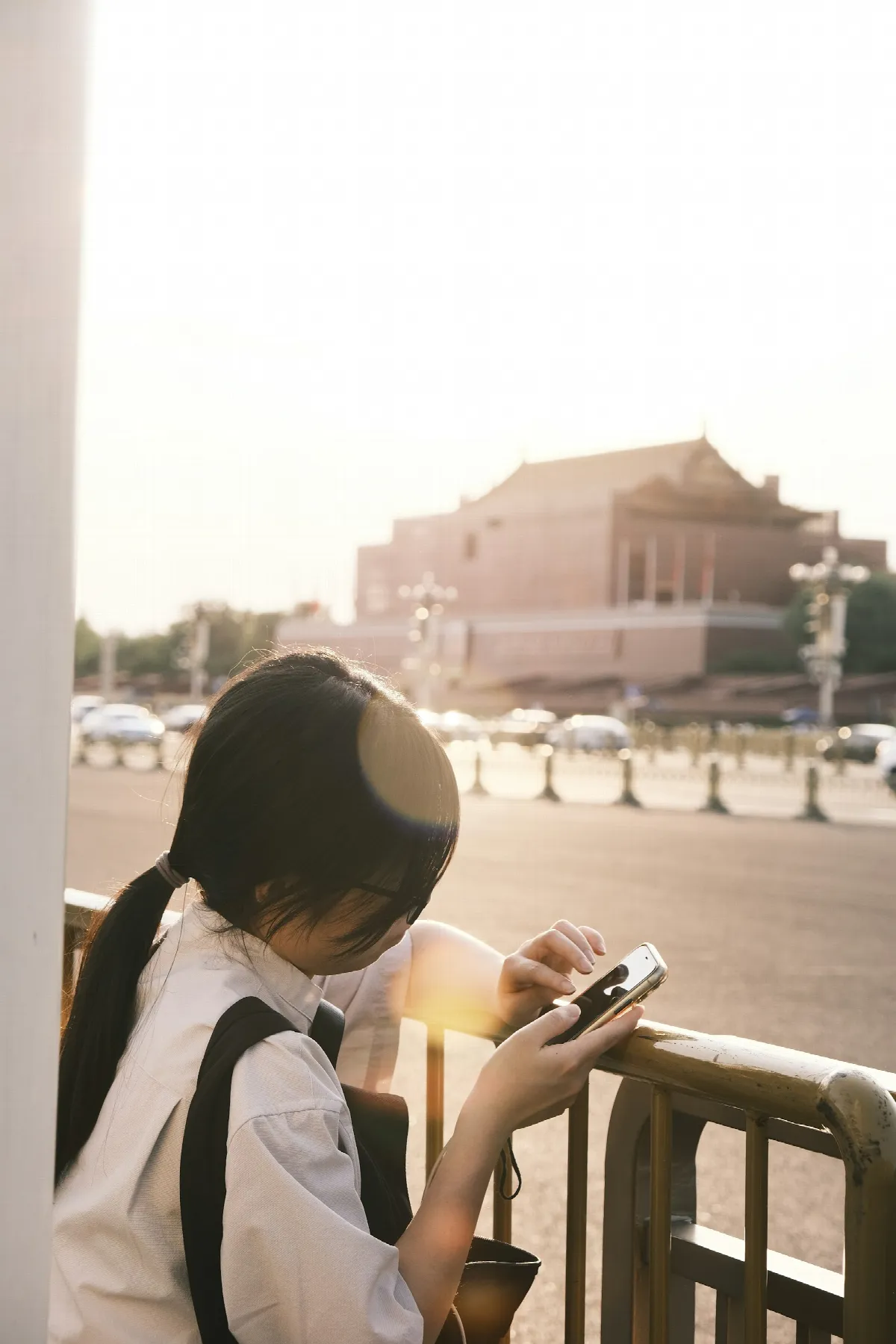 A young woman looks at her phone on a city street, the age when a thin credit file is most common