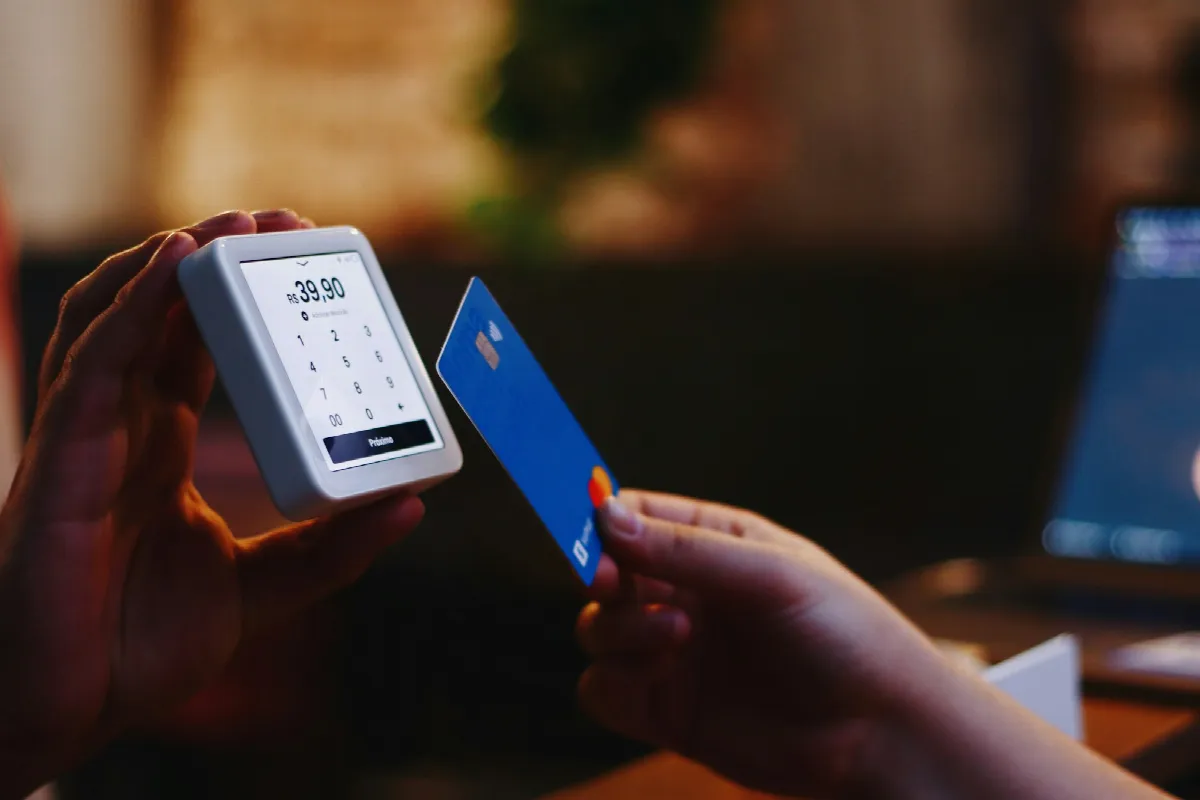 A person holding a credit card in one hand and a smartphone in the other, a reminder that card balances are part of what hurts your credit score
