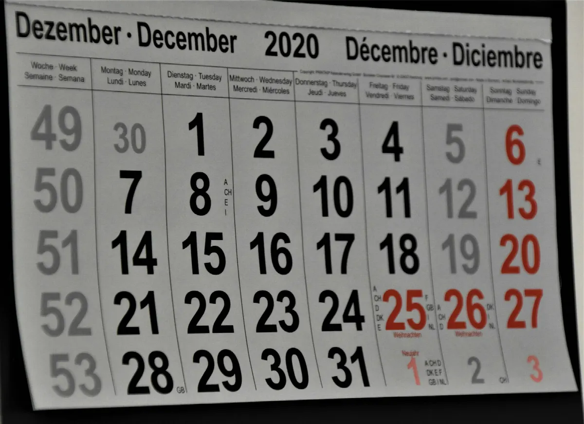 A black and white monthly calendar pinned to a white wall